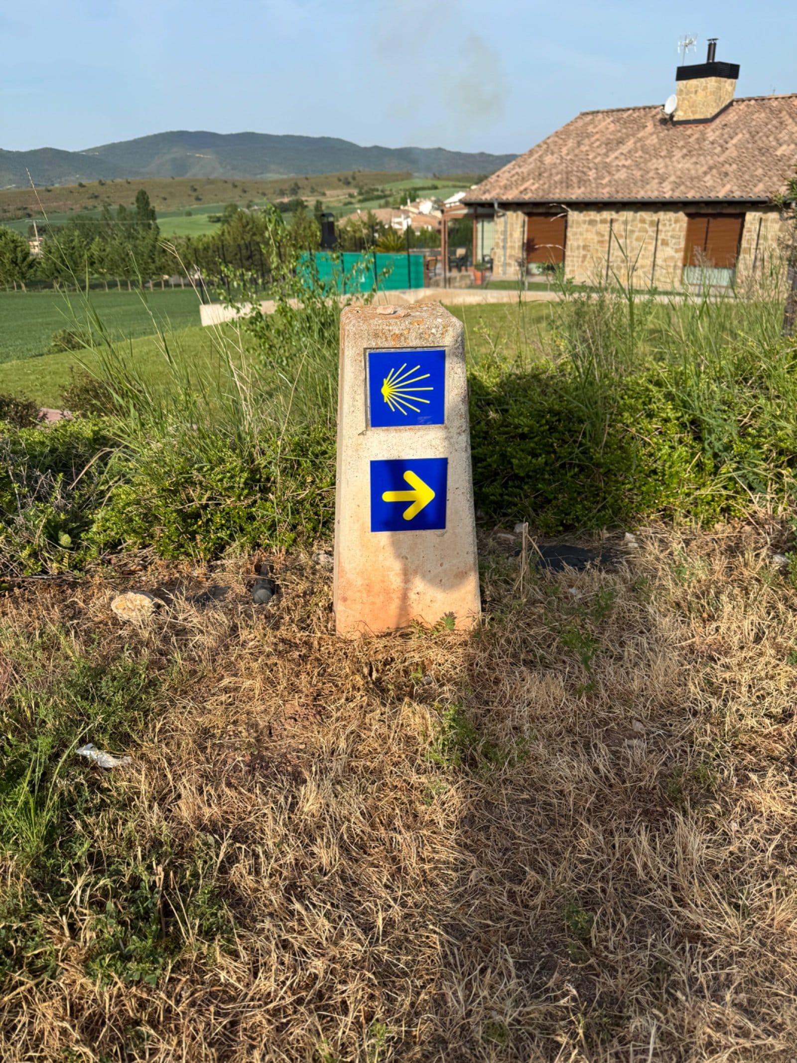 Concrete waymarker pillar with scallop shell and arrow