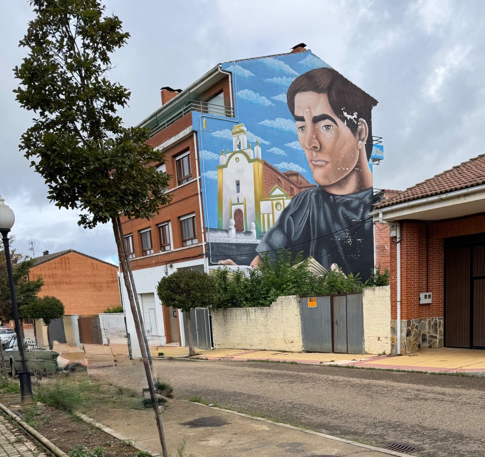 Village building with large portrait mural and church scene