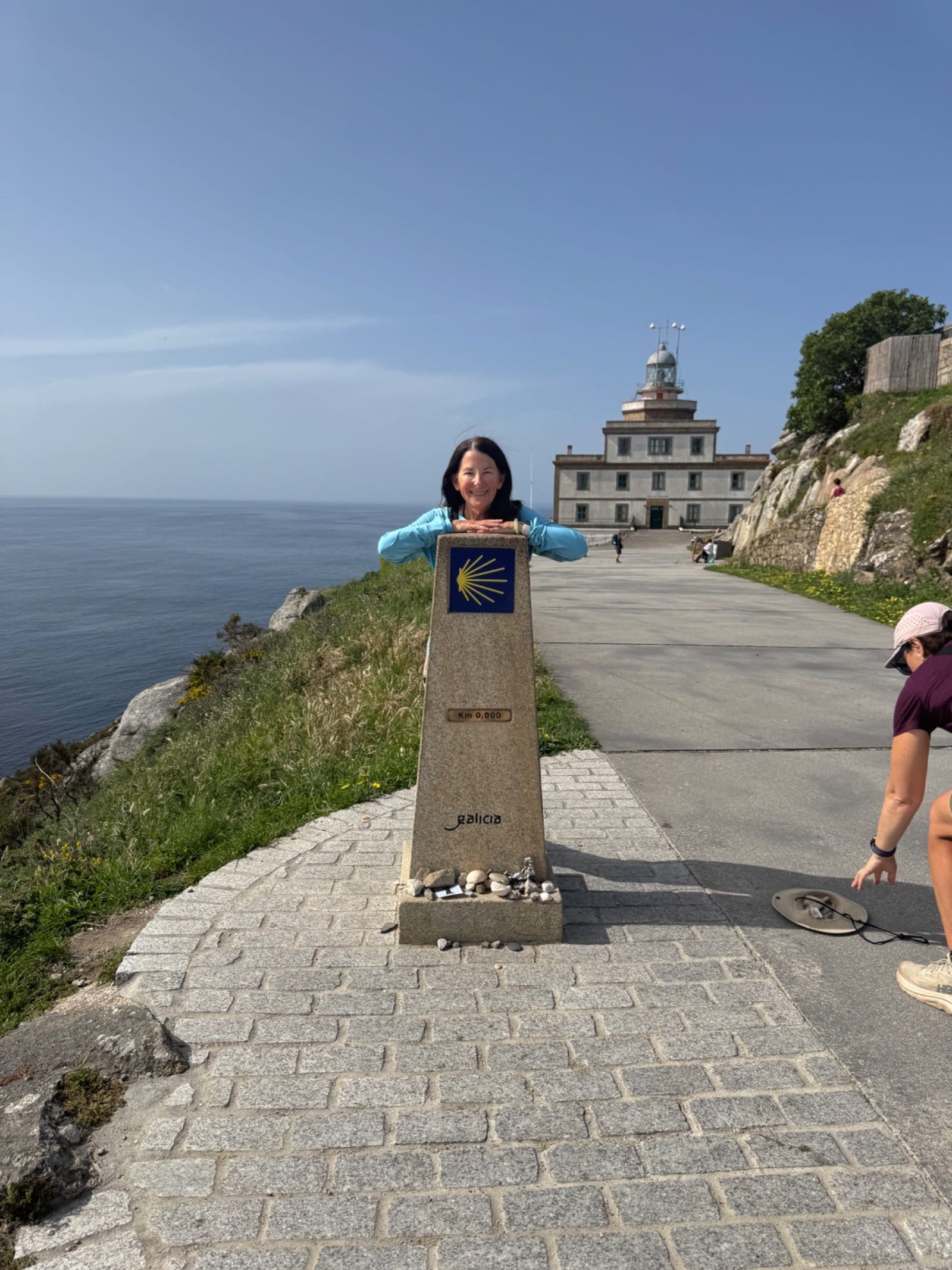 Shelley hugging Camino endpoint marker at Finisterre